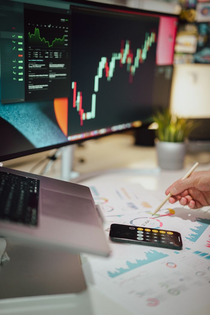 Insightful business analytics with graphs on monitor, papers, and phone calculator.