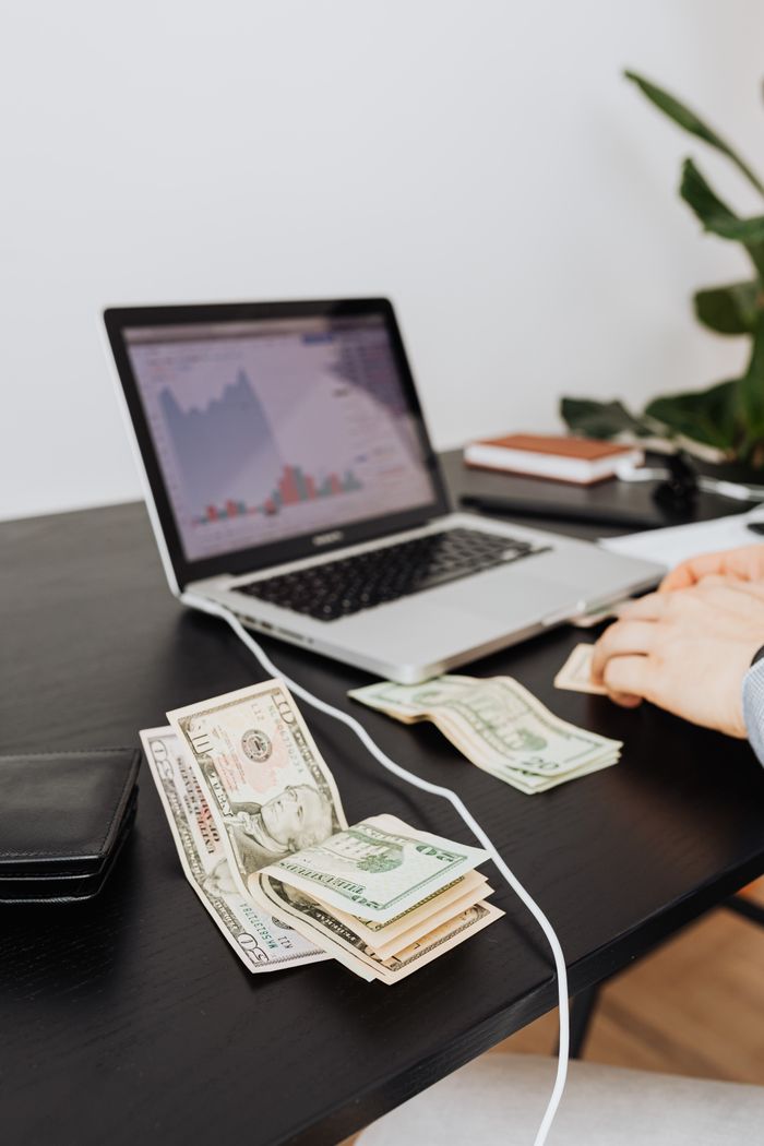 services-02 Money and laptop on desk indicating financial work or analysis. Perfect for business themes.