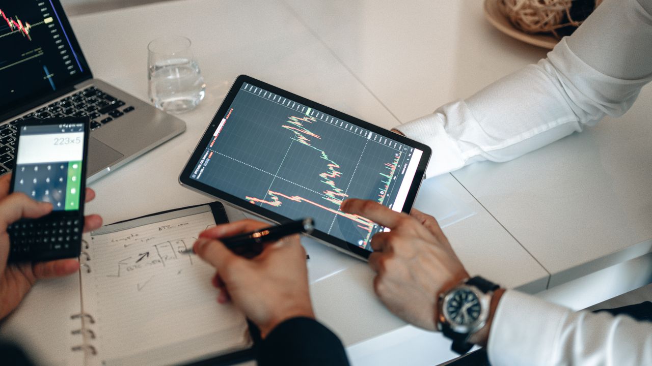 Team working on financial analysis using tablet and calculator in office.