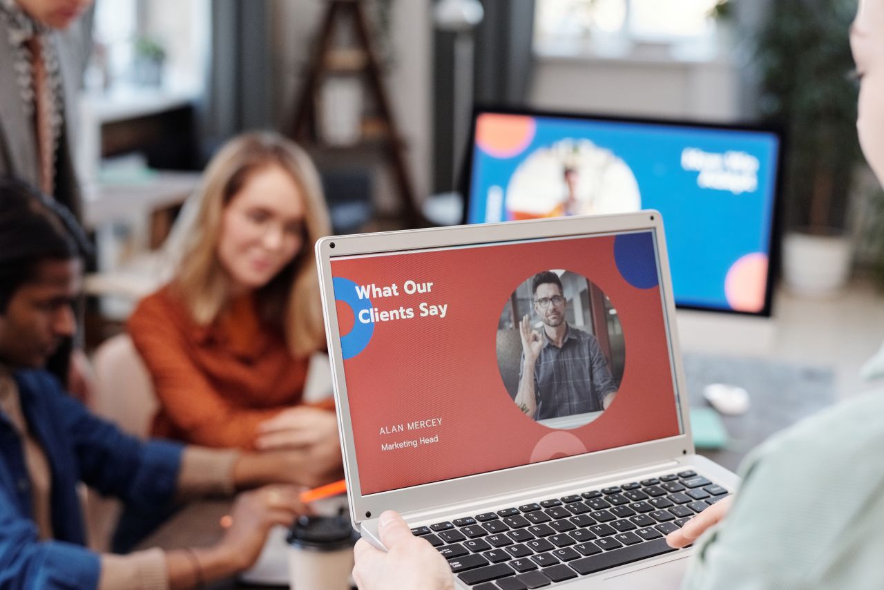 contact-img Diverse business team in a meeting analyzing client testimonial on laptop screen.